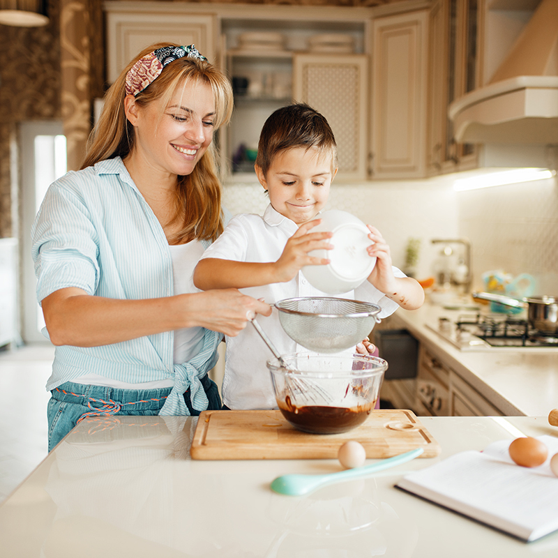 A mother and son mixing melted chocolate in a bowl
