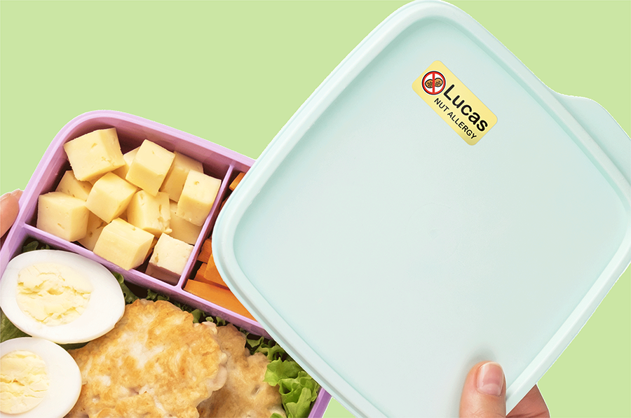 A lunchbox with a nut allergy name label, open to show food inside