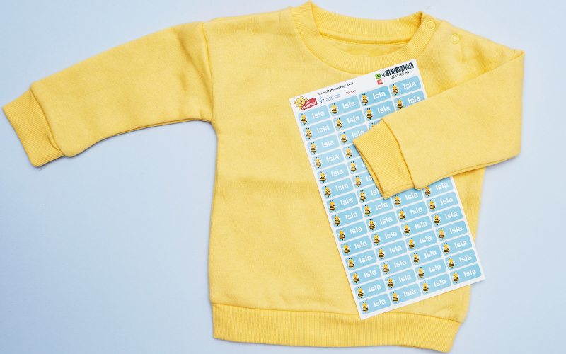 A yellow jumper with a sheet of My Nametags labels on a light grey background